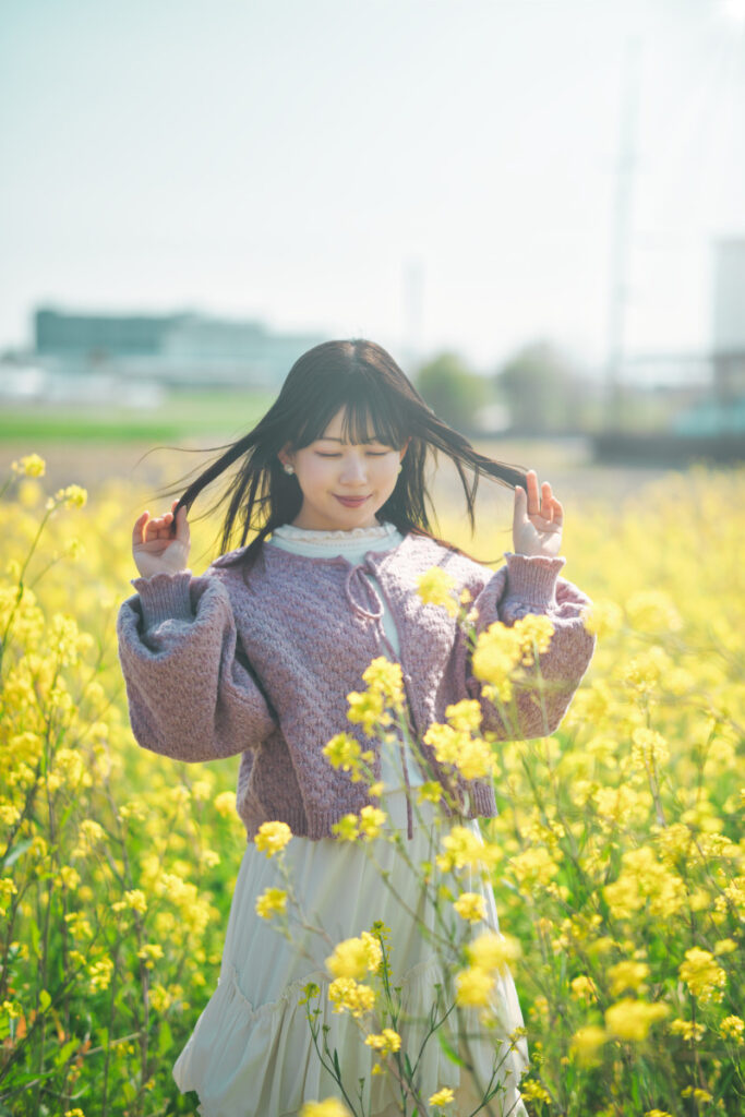 菜の花畑で目を閉じ、春の空気を感じるモデル・ぬぬ。情緒的な「記憶」としてのポートレートをLuminar Neoで創り出すための、静かな瞬間を捉えた記録