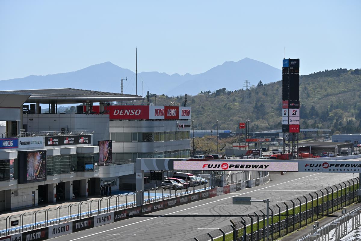 澄み渡る青空の下、富士山を背景に設置された「頭文字D」30周年記念の看板とイベント会場の様子