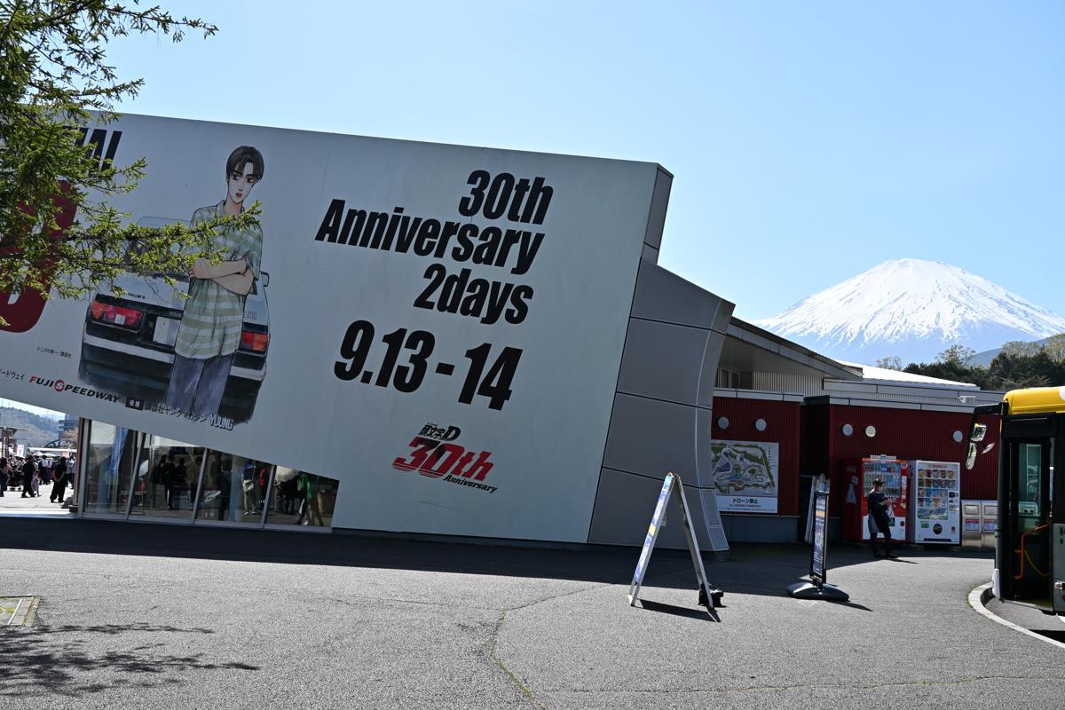 富士山と「頭文字D 30th Anniversary」の巨大な壁面広告が並ぶ富士スピードウェイの広場