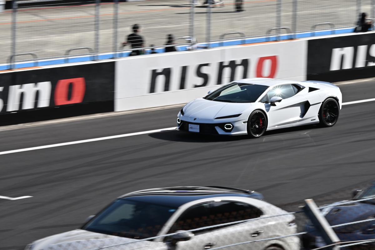 富士スピードウェイのコース上をハイスピードで走行する白いランボルギーニ・レヴエルト
