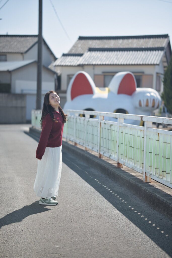 常滑市の遊歩道で、とこにゃんを背に全身と表情を捉えた花咲ゆいなさんの写真