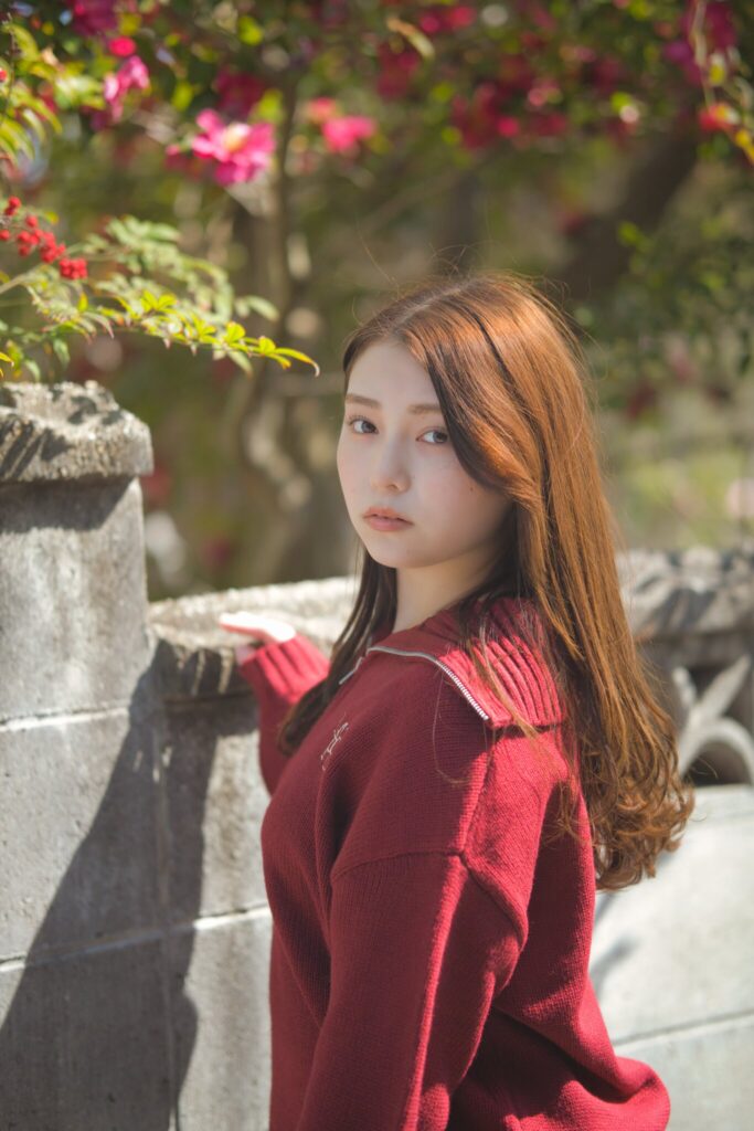 庭先の赤い実と梅の蕾を背景にした、冬と春が交差する風景の中の花咲ゆいなさん