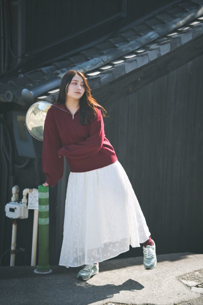 黒い壁が続く常滑の路地裏で、鋭い日差しと影の中に佇む花咲ゆいなさん