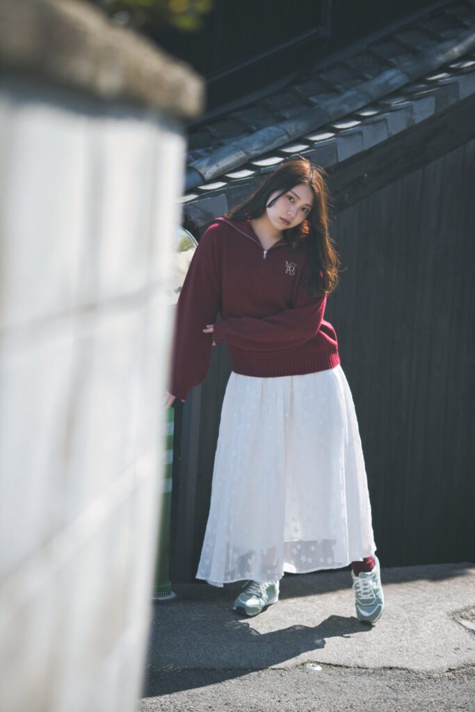 黒い壁が続く常滑の路地裏で、鋭い日差しと影の中に佇む花咲ゆいなさん