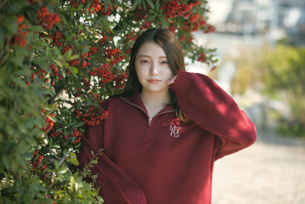 屋外で看板の前に座り、自然な表情を見せる花咲ゆいなさんの三段階のカット