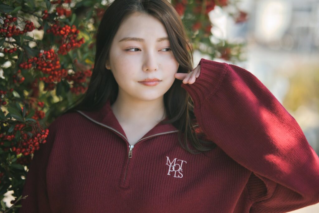 屋外で看板の前に座り、自然な表情を見せる花咲ゆいなさんの三段階のカット