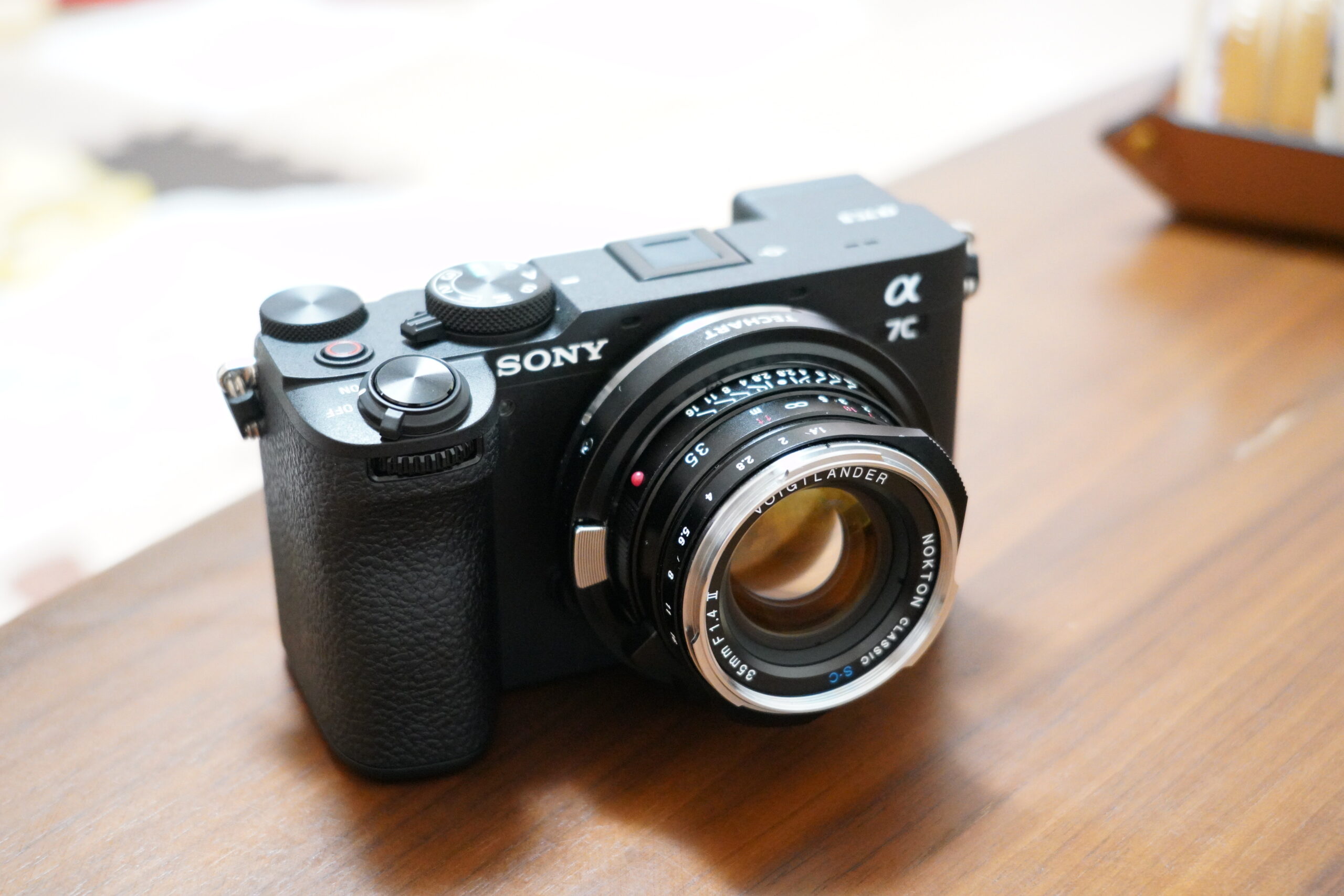 テーブルの上に置かれたSONY α7CIIと、コンパクトな単焦点レンズの外観