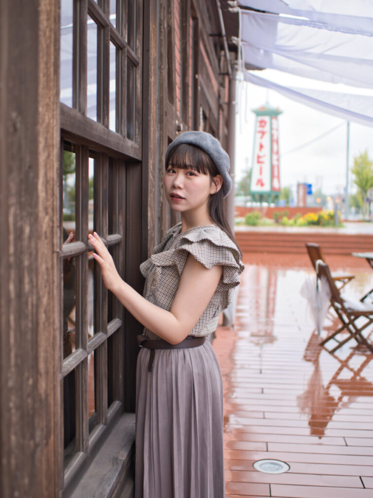 雨上がりのレンガの質感と濡れた床に立つゆめのさんを捉えたポートレート。LUMIX G100Dの「撮って出し」の底力。