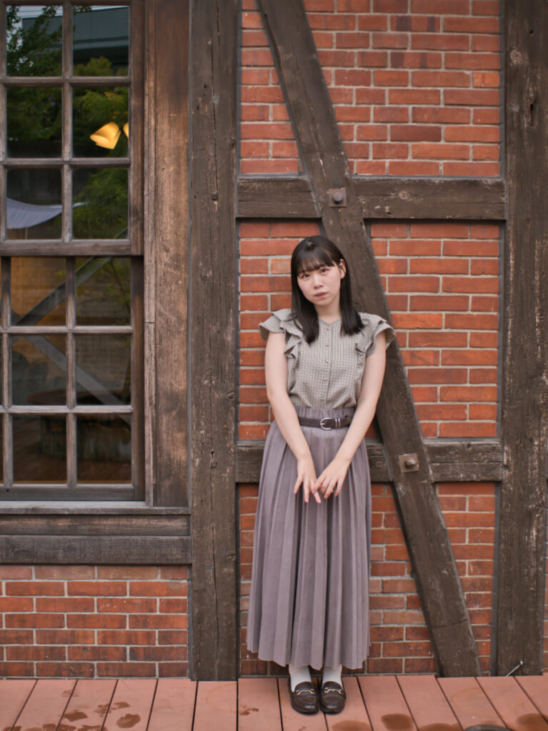 雨の日の外光を利用し、レンガの質感とゆめのさんの笑顔を捉えたポートレート。LUMIX G100Dの「撮って出し」の底力。