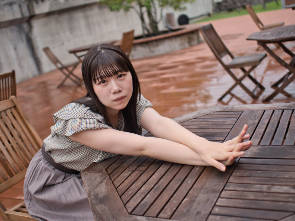 椅子に腰かける、ゆめのさんのポートレート。20mm F1.4 PRO特有の柔らかな前ボケが、画面全体に奥行きを生み出す。