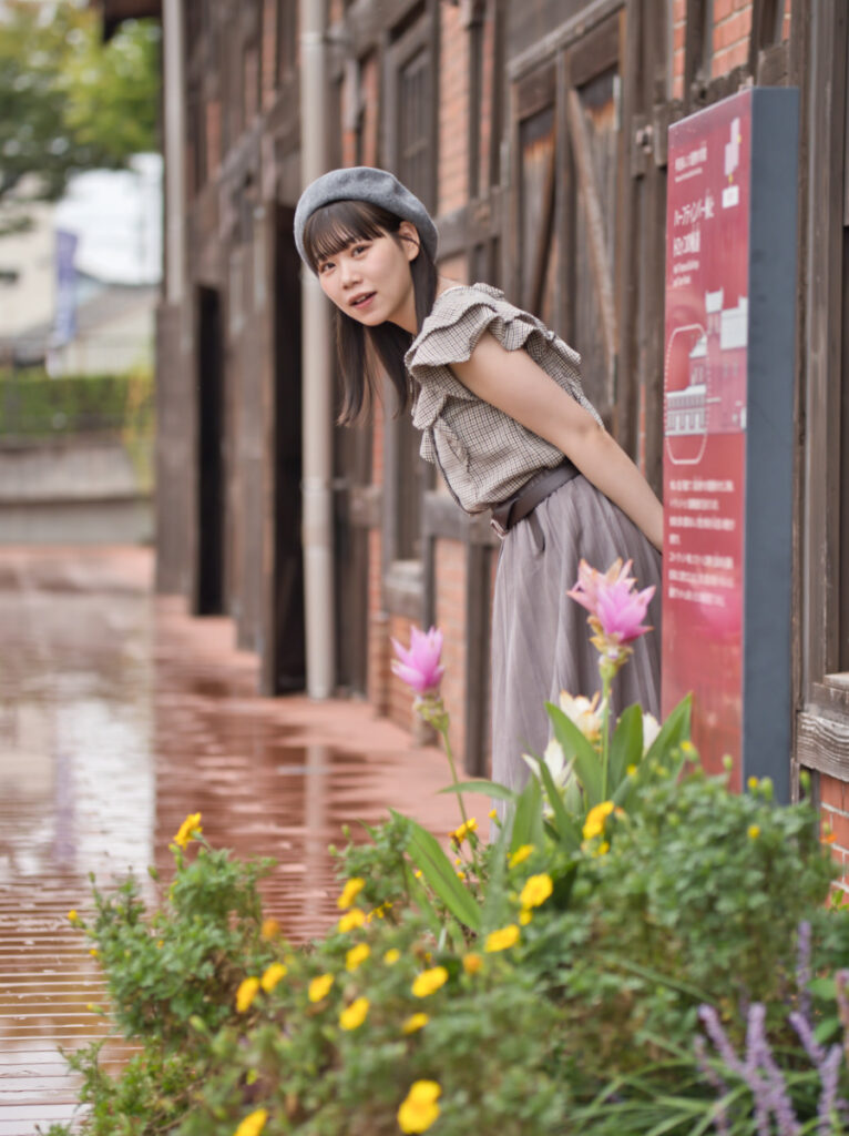 花の前で、カメラを見つめるゆめのさんのアップ。F1.4の明るさが広げる、ポートレート撮影の表現幅。