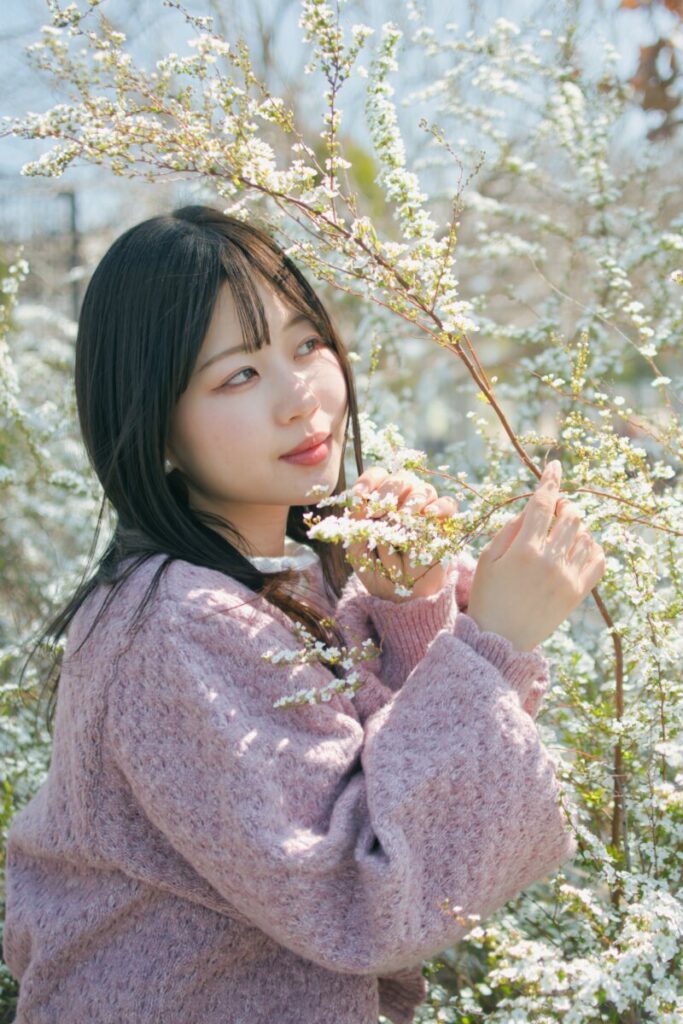 白い花(ユキヤナギ)の並木道で、花に優しく触れながら横を向くモデル・ぬぬのポートレート。Luminar Neoの「アトモスフィアAI」で神秘的な空気感を加える前の原版。