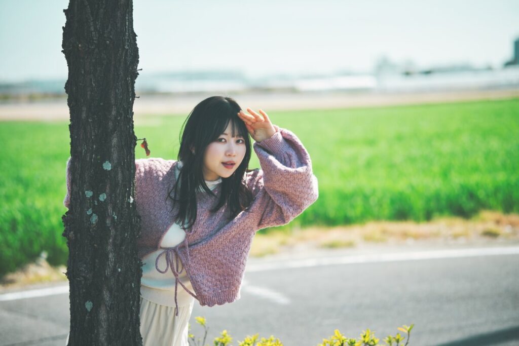 木の側で眩しそうに手をかざすモデル・ぬぬ。Luminar NeoのAI技術で、強い日差しの中でも表情を自然に明るく補正するための現像前ベース画像。