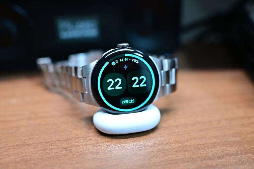 専用スタンドで横置き充電中のPixel Watch 4。時刻が大きく表示され、デスク時計として機能している