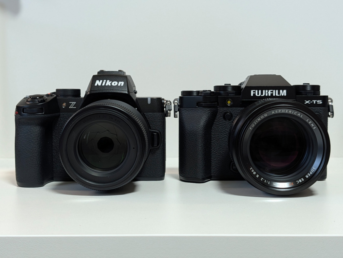白いデスクに並んだNikon Z50IIとFujifilm X-T5の正面比較写真。レンズが装着された2台のミラーレスカメラ。