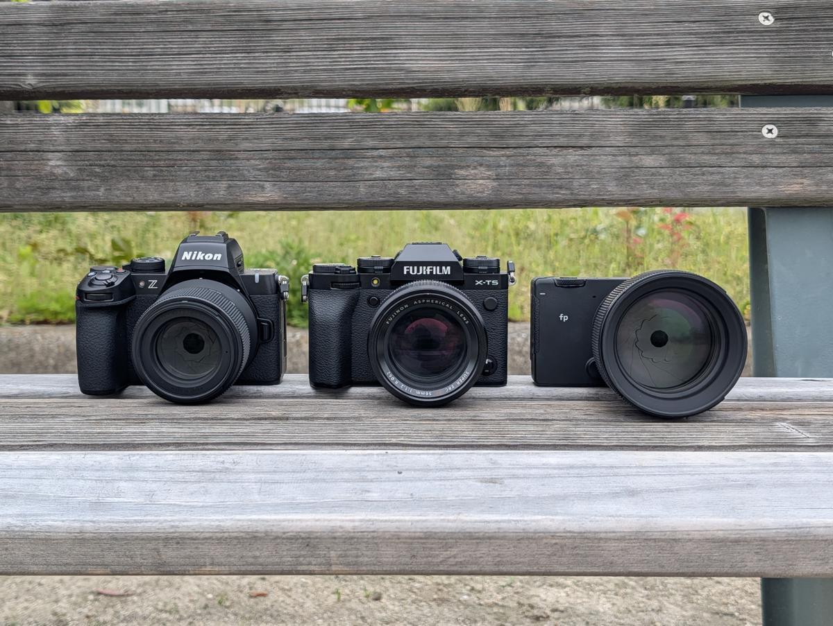 公園のベンチに並んだNikon Z50II、FUJIFILM X-T5、SIGMA fpのカメラ3台と、それぞれの装着レンズ（SIGMA 56mm F1.4、FUJINON 56mm F1.2、SIGMA 85mm F1.4）。
