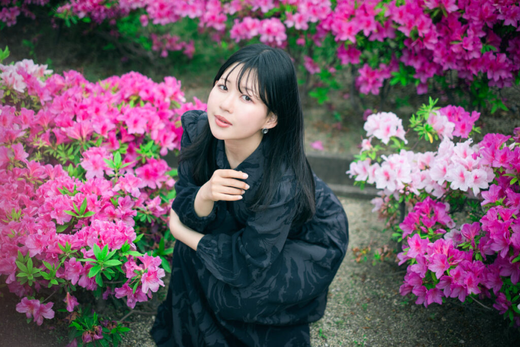 XF35mmF1.4 Rの柔らかな前ボケを活かし、ピンク色のツツジの中から浮かび上がるように写るモデルのぬぬさんの幻想的な写真。