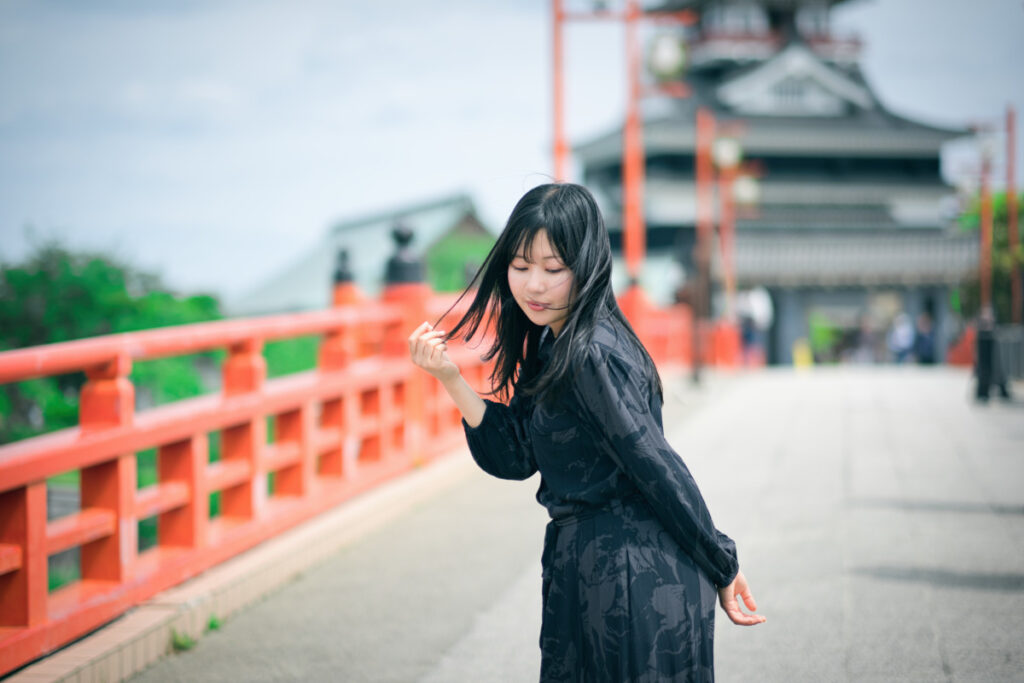 XF56mmF1.2 Rの柔らかな描写で、清州城の橋の上で風に吹かれながら目を閉じるぬぬさんの情緒的な横顔。