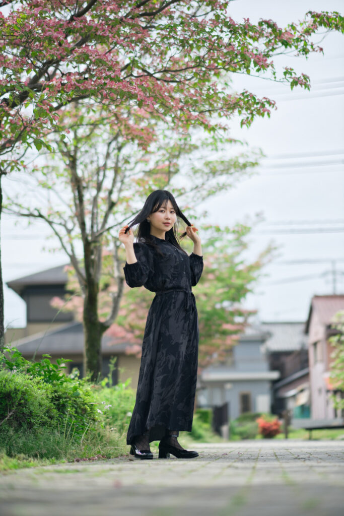 XF56mmF1.2 Rの発色の良さを活かし、ハナミズキのピンク色と新緑、そして黒衣のコントラストを捉えたポートレート。