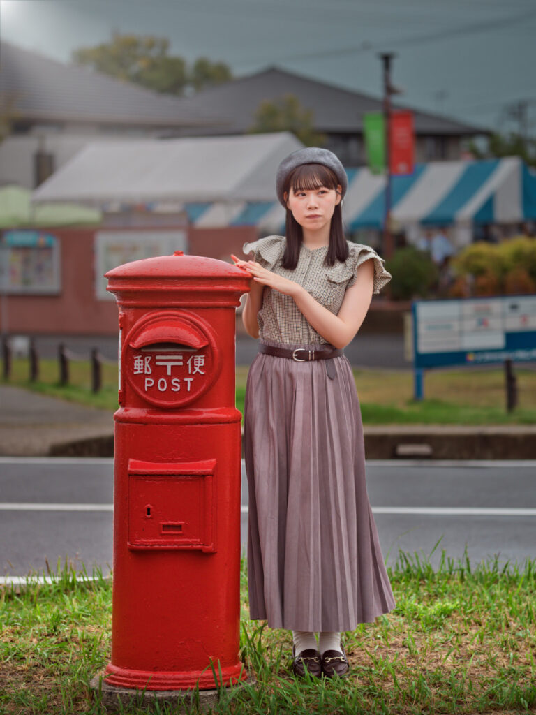 赤いポストの横に立つモデルの石原ゆめのさんに、Luminar Neoで生成した自然な太陽光線が降り注ぐドラマチックな現像例