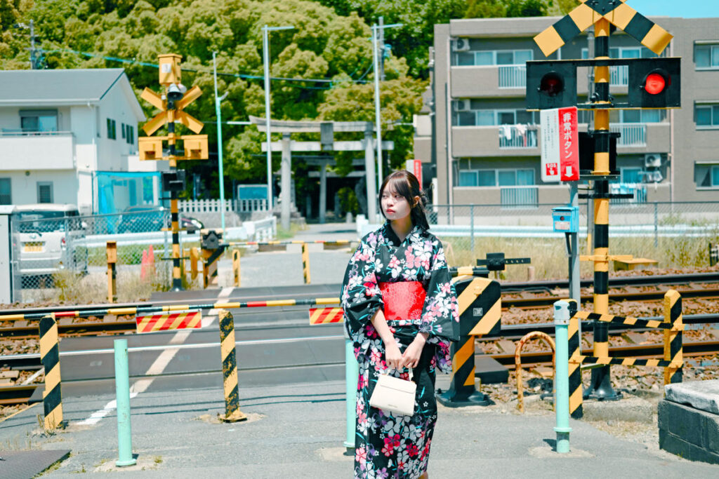 踏切前で電車の通過を待ちながら、ふと遠くを見つめる浴衣姿のみゆきさん