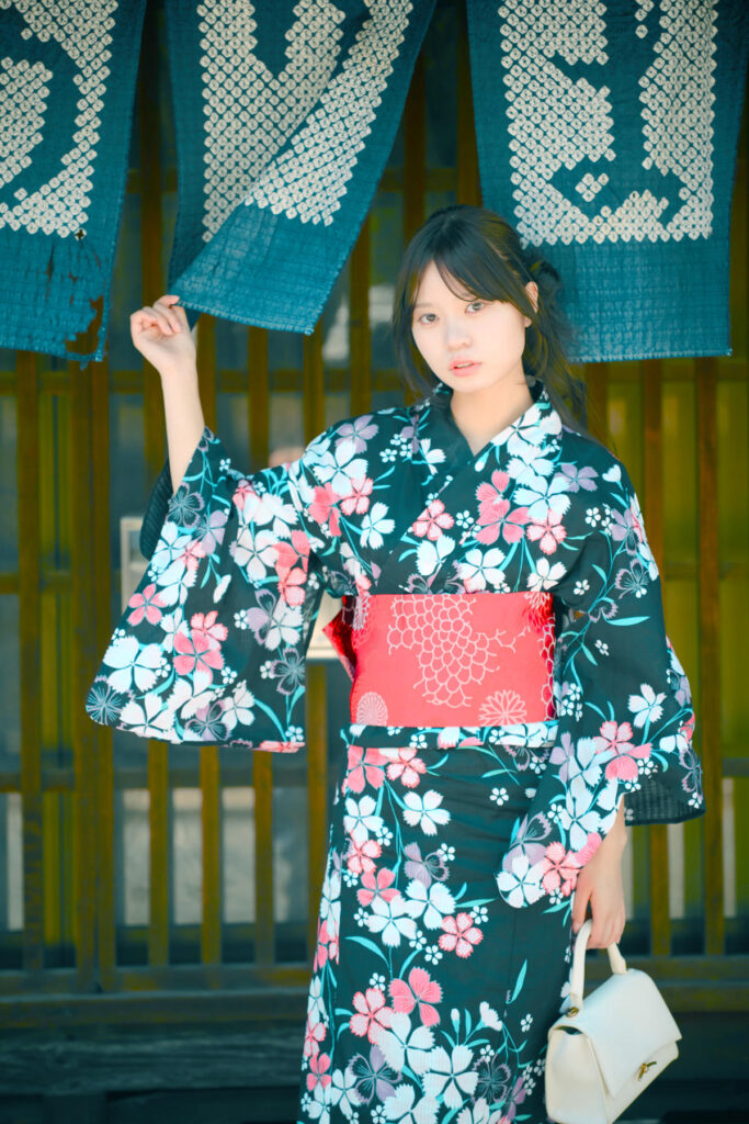 藍染の暖簾越しに、アンニュイな表情を見せる海月みゆきさんのアップ