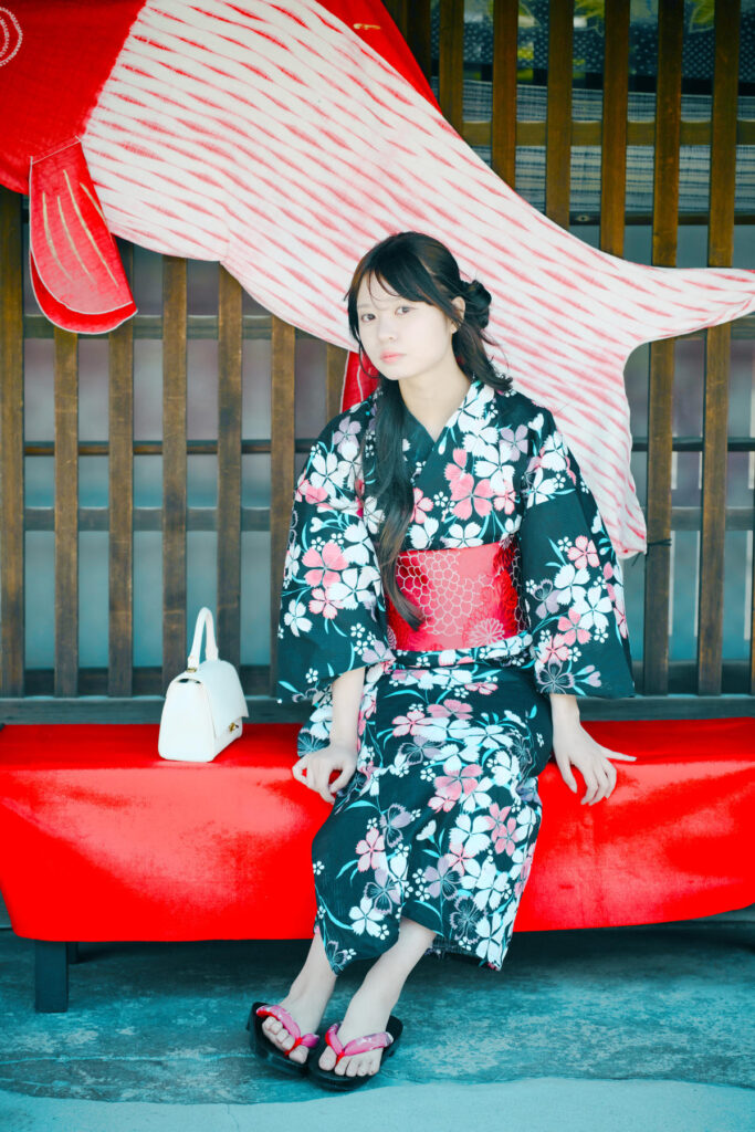 鯉のぼりの前でベンチに座り、伏し目がちに微笑む海月みゆきさん