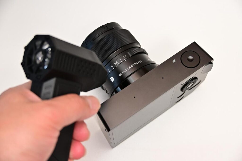 ハンディタイプのエアーブロワーを使い、SIGMA bfとレンズの隙間にあるホコリを吹き飛ばしている様子