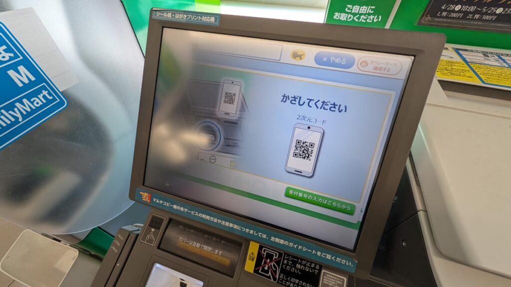 マルチコピー機の画面にスマホの2次元コード（QRコード）をかざす案内が表示されている様子
