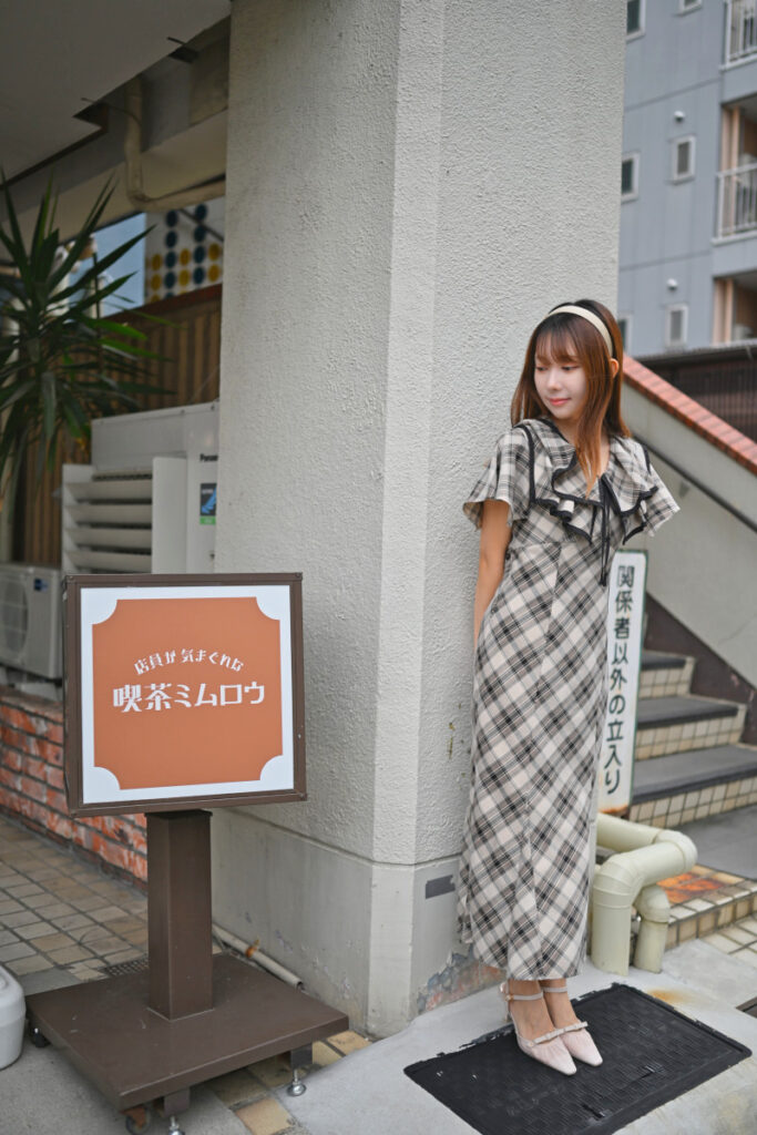 看板の文字を残しつつ柱に寄り添う菜穂さんの綺麗な立ち姿を捉えた写真