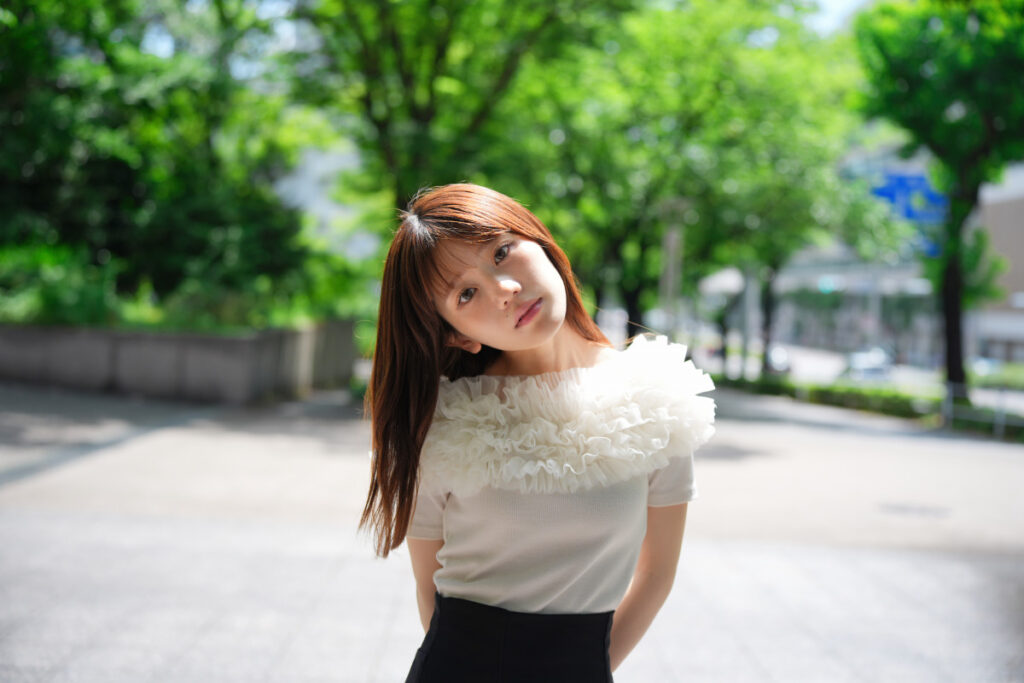 45mm標準域を使用しカメラを斜めに傾けて撮影した都会のストリートに佇むモデルこもれびもかさんのスナップ