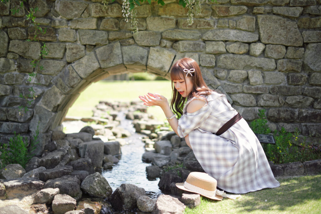 すくった水を愛おしそうに見つめる鹿乃ばんびさんと、トンネルの奥へと抜けていく小川のなだらかな遠近感ボケ。
