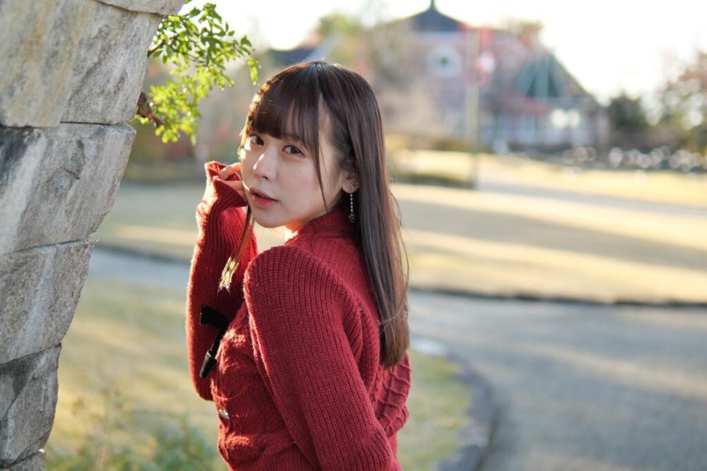 石のトンネル下で、片手を頭に添えてこちらを見つめる鹿乃ばんびさんの全身ポートレート。