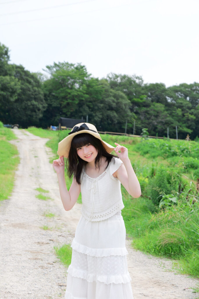 75mm望遠端:一本道の真ん中で帽子に手を添える女性モデルのポートレート