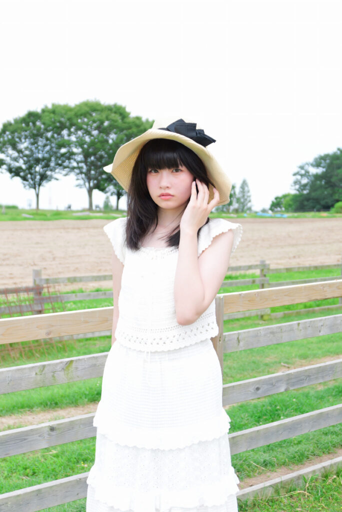 50mm標準画角:ひまわりの黄色い花に囲まれて微笑む女性モデルのポートレート