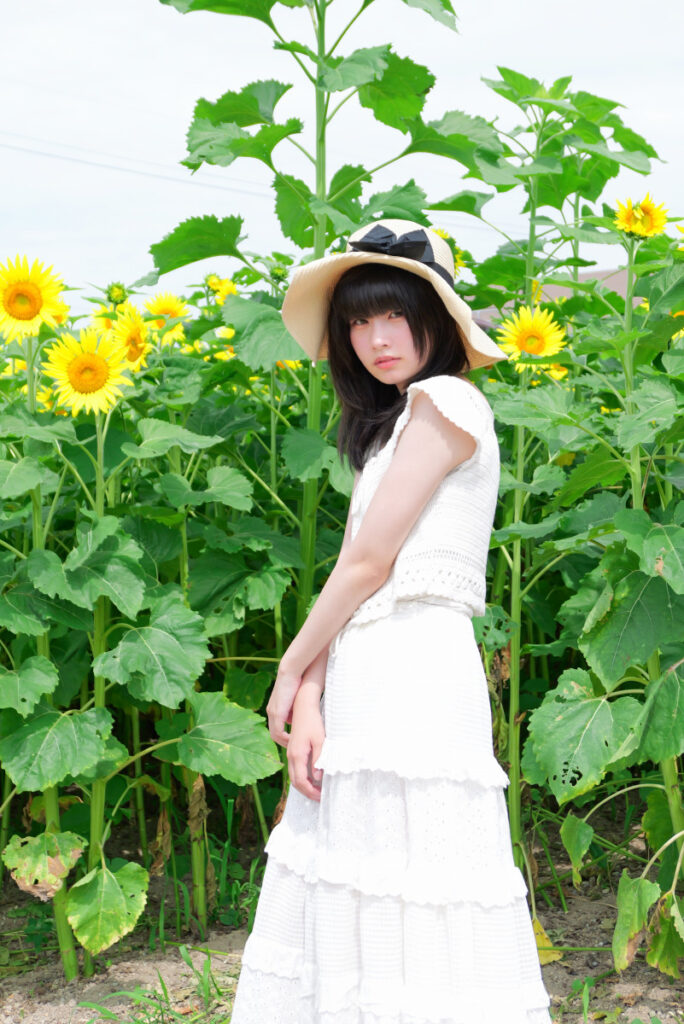 50mm標準画角:ひまわりをバックに立つ女性モデルの正面アップ