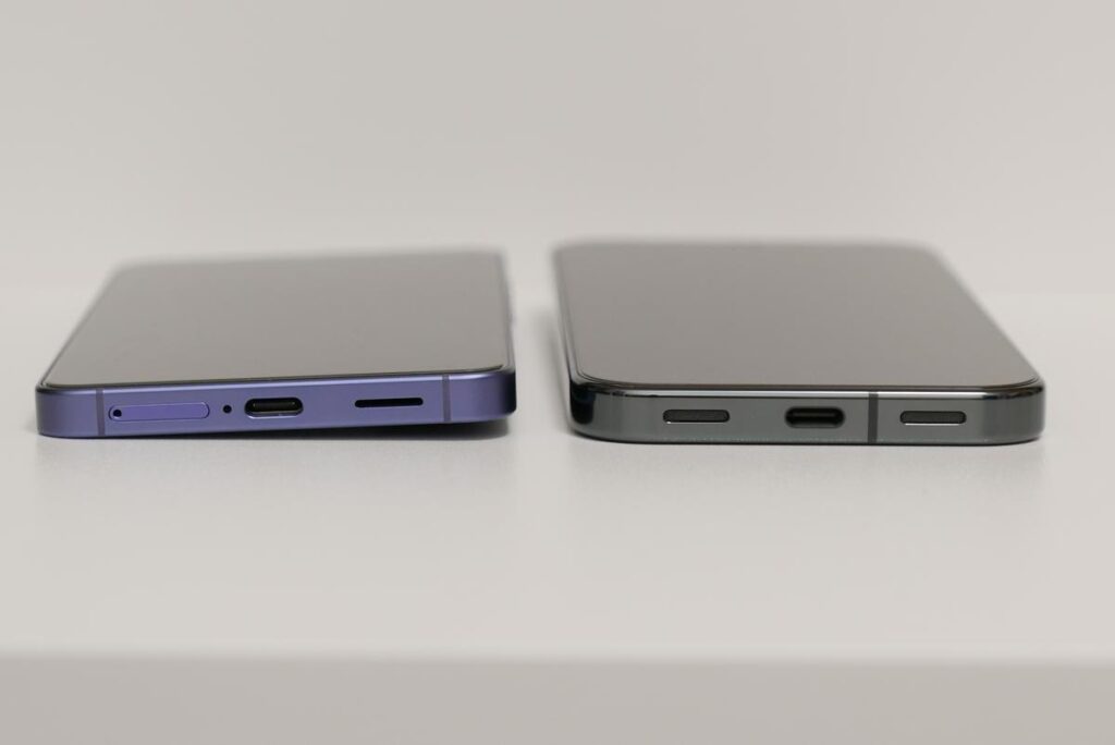 Pixel 10 Proの美しい鏡面仕上げの側面フレームとGalaxy S26の薄い底面スピーカー・USBポート側を並べた比較写真