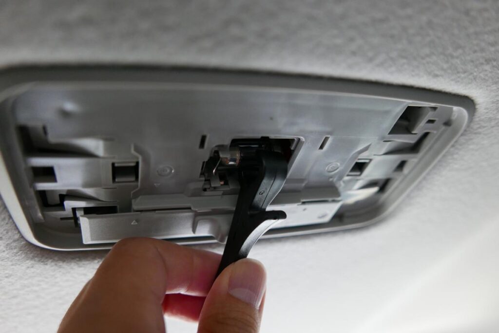 リヤルームランプユニット内の純正電球に黒い取り外し治具を差し込む様子