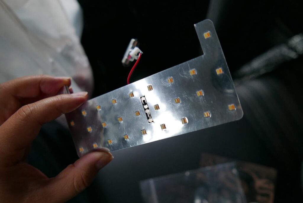 手のひらに載せたアクアのリヤセンター用面発光LED基盤と接続端子