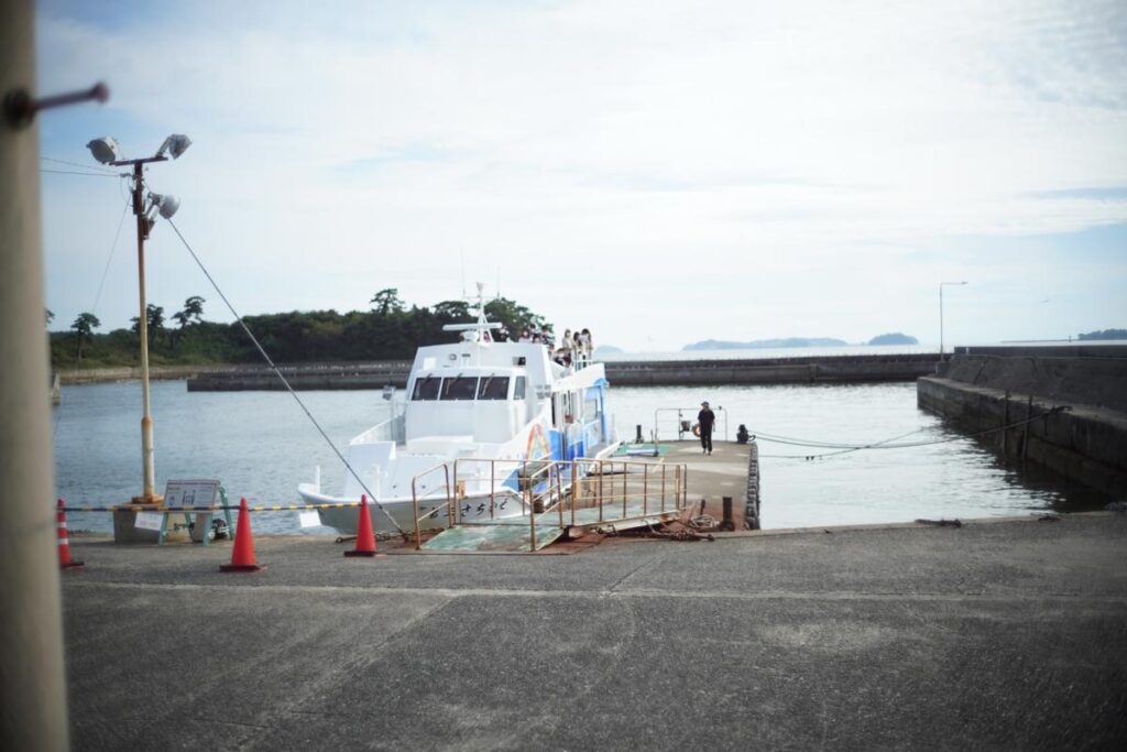 佐久島の港に停泊する白い定期船と、オールドレンズ特有の温かみのある琥珀色の景色