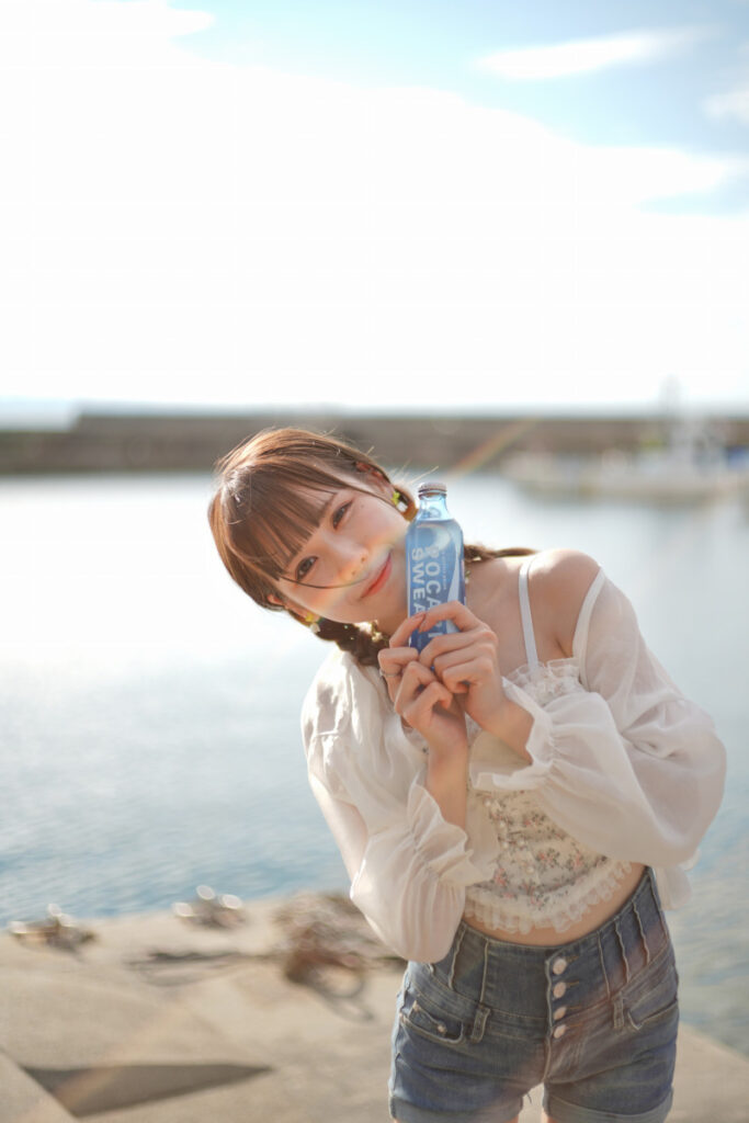 前髪に美しいフレアの光が重なる、カメラに向かって首を傾げて微笑む鹿乃ばんびさん