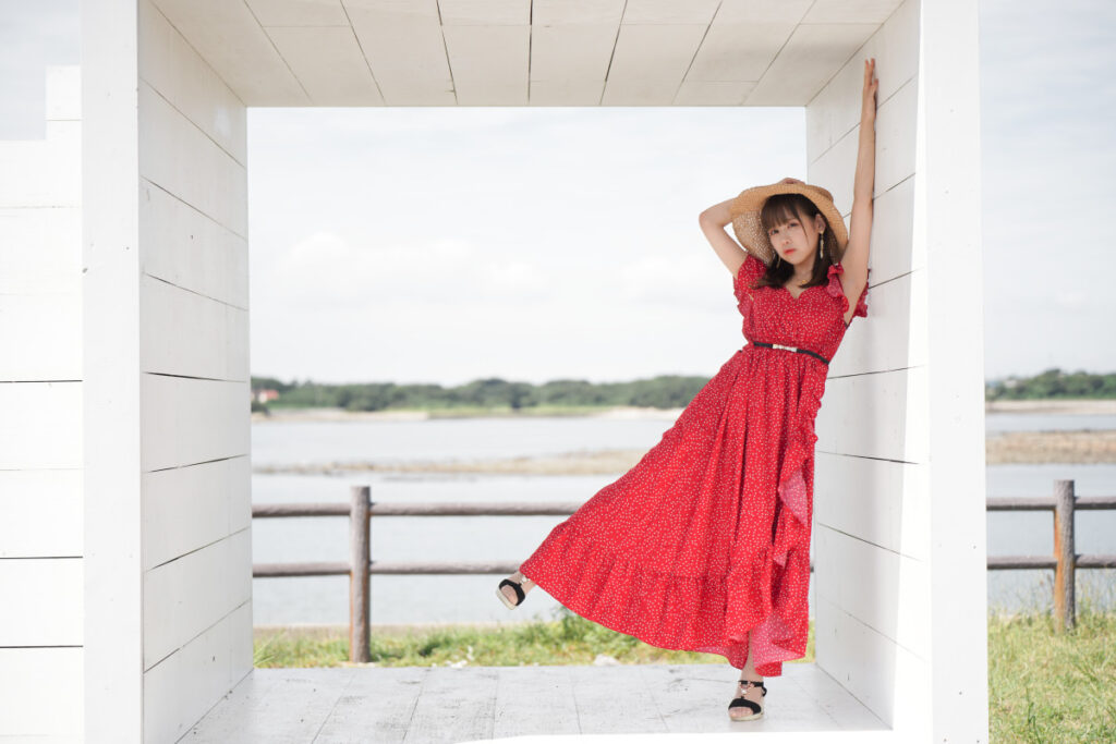 「白い箱」の壁に寄り添い、麦わら帽子に手を当ててポーズをとる鹿乃ばんびさんの全身カット