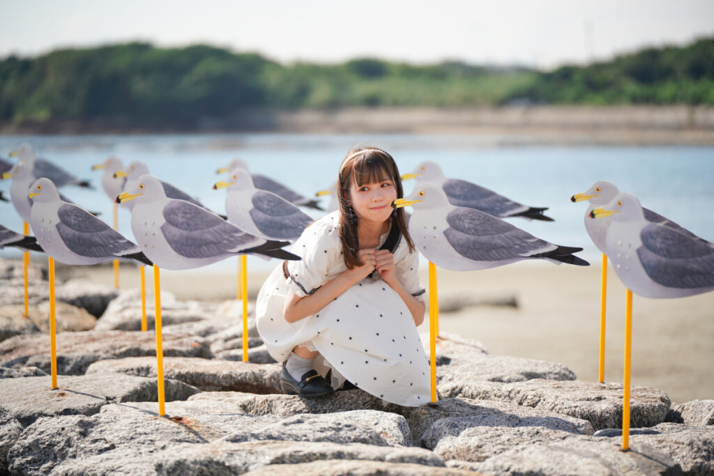 カモメのオブジェの横で両手を胸の前で握り、はにかんだ笑顔を見せる鹿乃ばんびさん