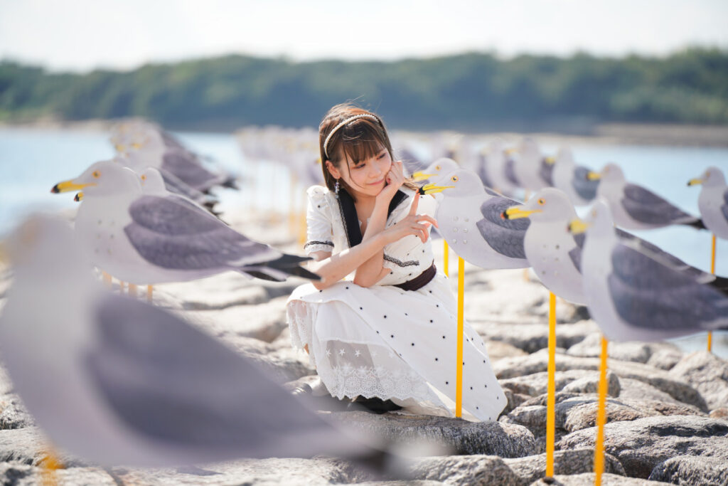 カモメのくちばしにそっと人差し指を近づける、背景が滑らかにボケた鹿乃ばんびさんの印象的なポートレート