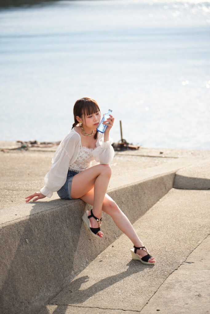 夏の強い逆光の中で、青いポカリスエットのボトルを口元に寄せる鹿乃ばんびさんのドラマチックな横顔カット