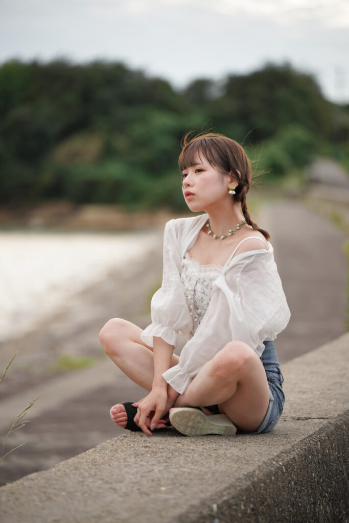 堤防の上にしなやかにあぐらをかいて座り、夕暮れの海を見つめる鹿乃ばんびさん