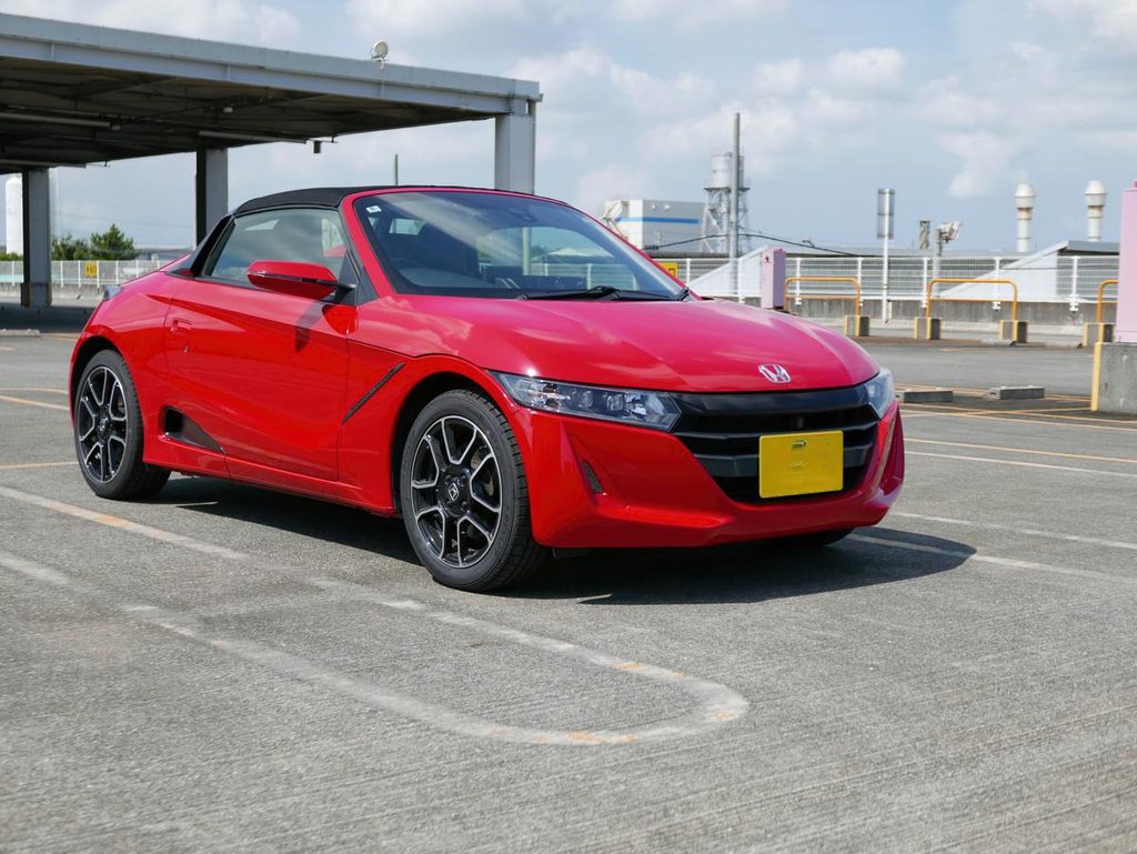 青空と駐車場に映える赤いホンダ S660 後期型のフロントクォータービュー