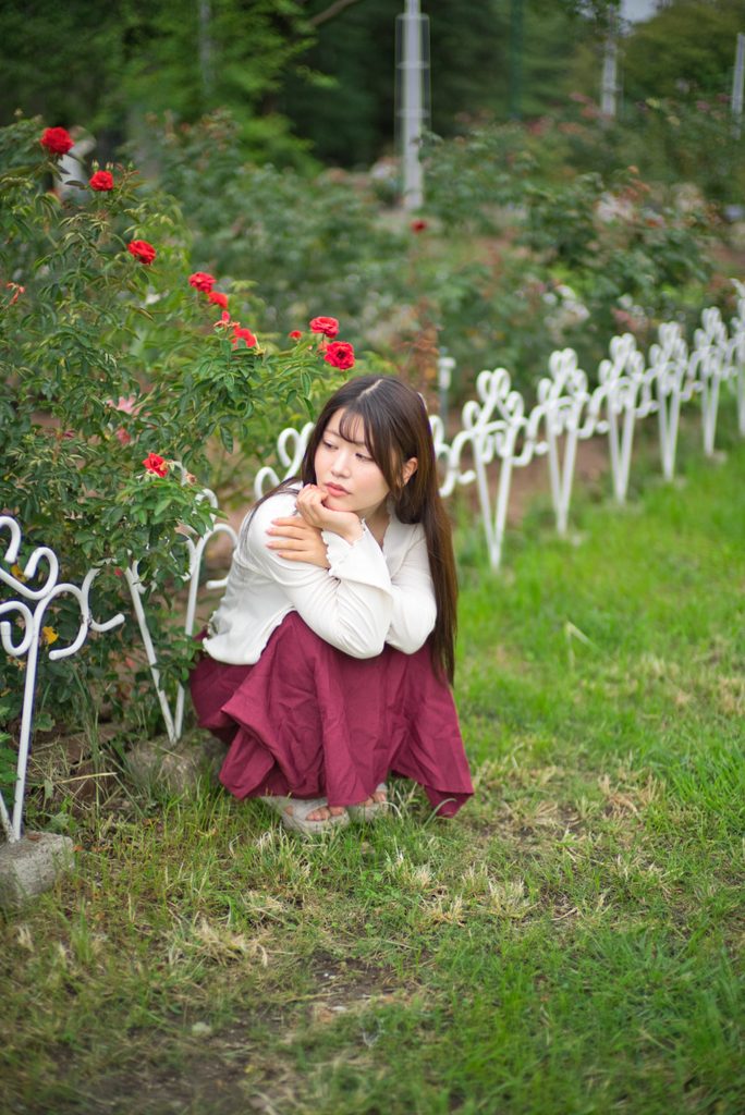 バラとアイアンフェンスに寄り添う桜井こはるさんのポートレート(開放F1.0)