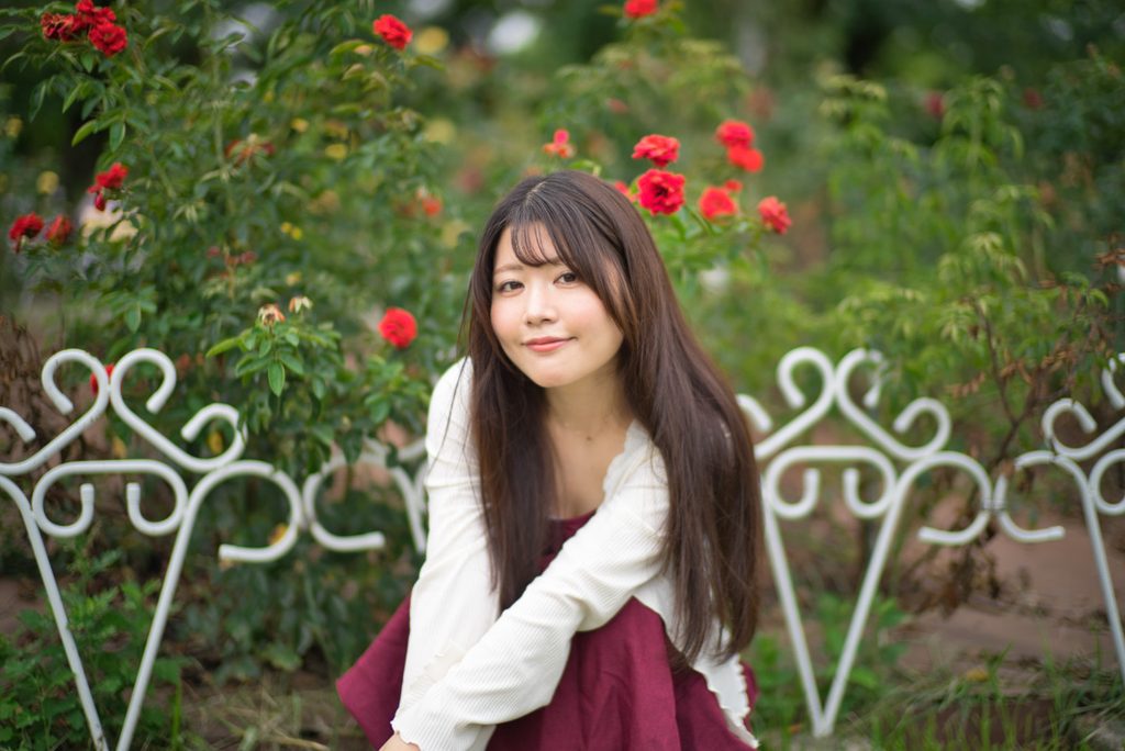 バラ園のフェンス前で微笑む桜井こはるさんの開放F1.0作例