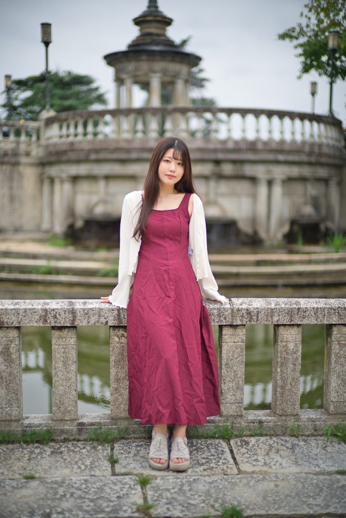 鶴舞公園の噴水塔を背景にした桜井こはるさんの全身ポートレート(開放F1.0)